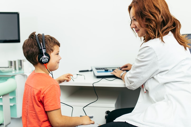 Audiologist performing hearing test on child patient