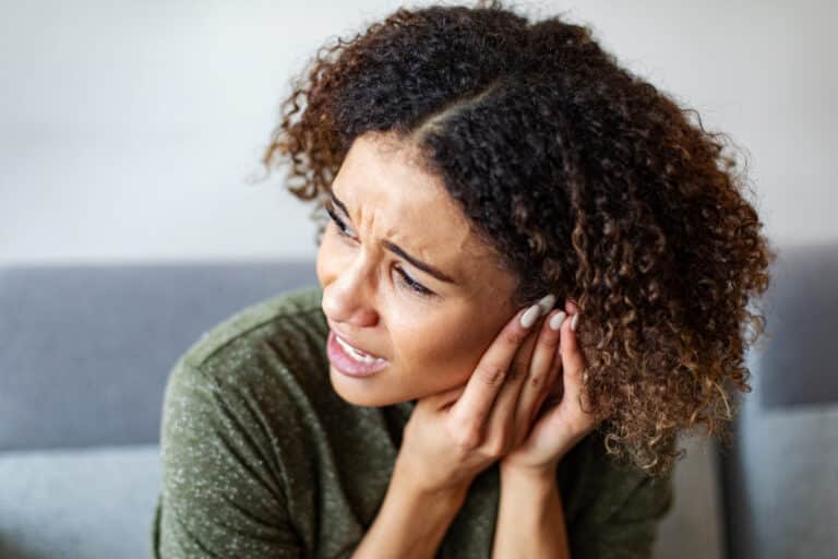 Woman with an ear infection pressing her ear.