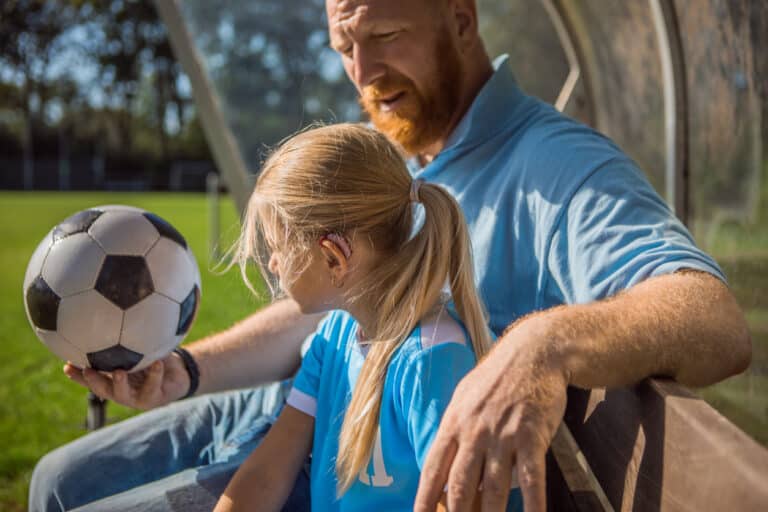 Young girl wears hearing aid while playing soccer