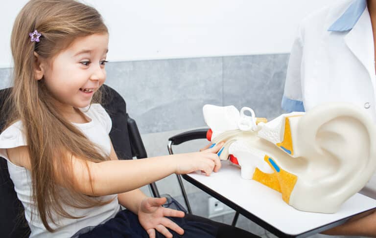 Young girl pointing at a model of an ear in their doctor's office