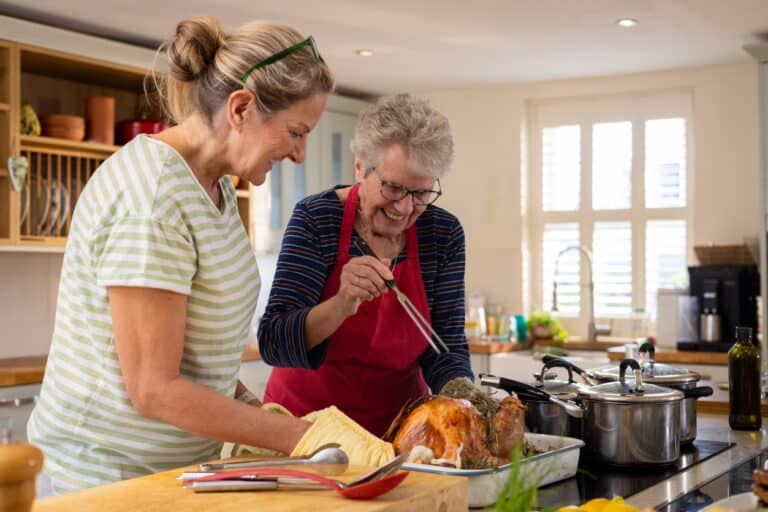 Senior woman and her daughter basting a turkey