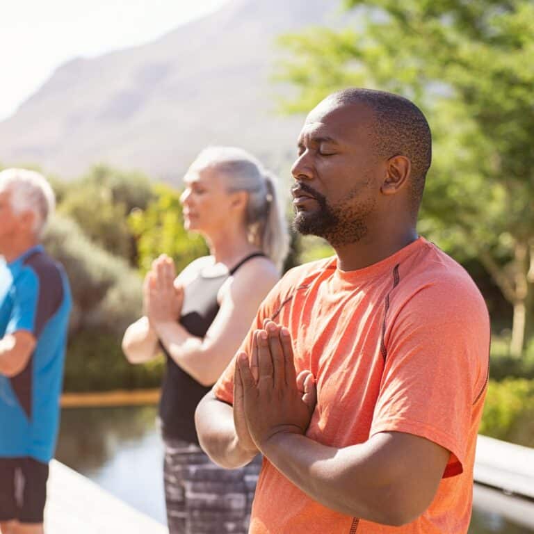 Man in an exercise group meditating in a park Man in an exercise group meditating in a park